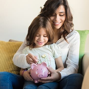 Mother and daughter placing change in a piggy bank