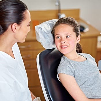 Little girl in dental chair smiling at mom