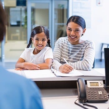 Mother and daughter checking in at reception desk