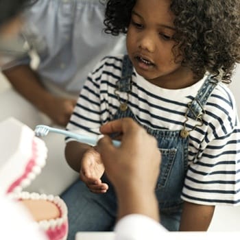 dentist showing a child how to brush their teeth