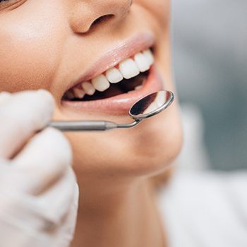 Dentist using small mirror to examine patient's teeth