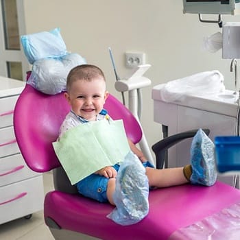 A little boy seated in the dentist’s chair and preparing to have a fluoride treatment