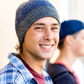 A male teenager wearing a beanie and showing off his newly repaired smile