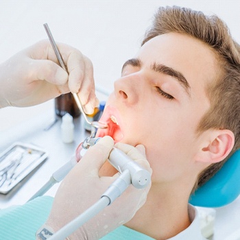 A male teenager allowing a dentist to look in his mouth to determine if he needs a frenectomy