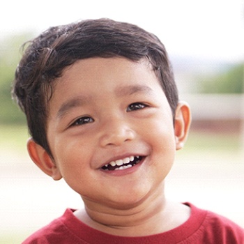 A happy and smiling little boy wearing a red t-shirt