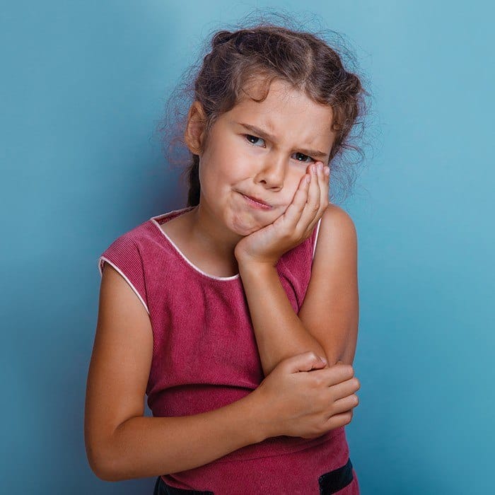 Little girl holding cheek