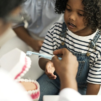 A dentist in Duncanville showing a child how to properly brush their teeth