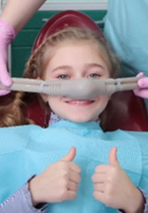 Child giving thumbs up while inhaling nitrous oxide