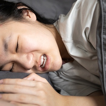 Young girl in bed, grinding and clenching her teeth