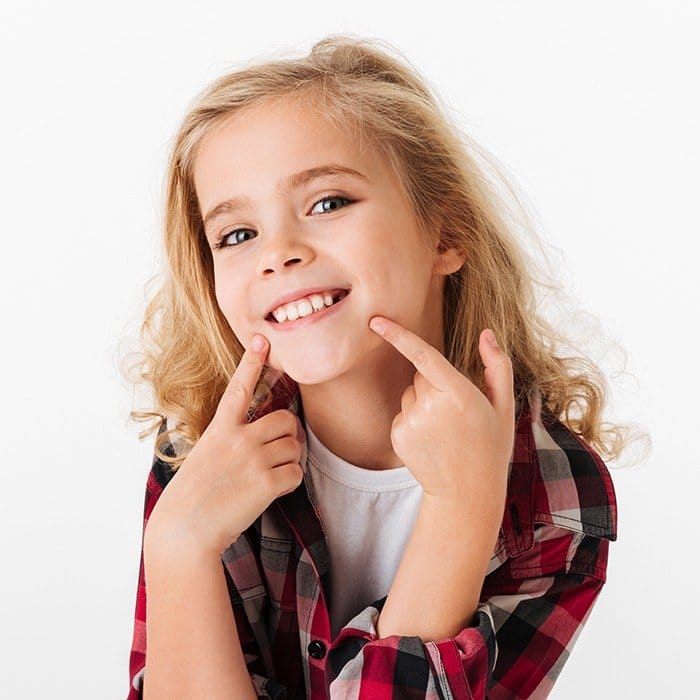 Young girl pointing to smile