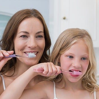 Mother and daughter brushing teeth together