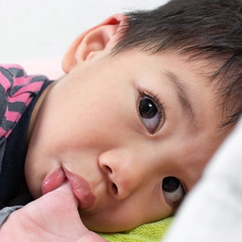 A young boy lying in bed and sucking his thumb in Duncanville