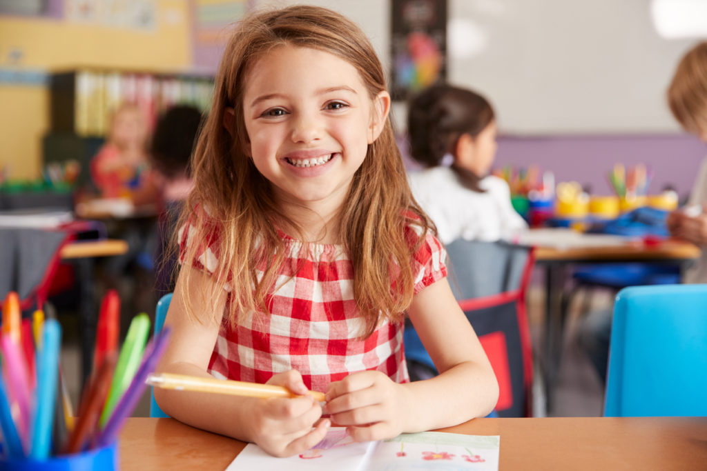 Child smiling while completing work in classroom