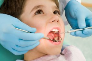 Dentist examining a little boy's teeth with dental instruments