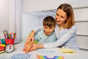 Mother doing craft with special needs child. 