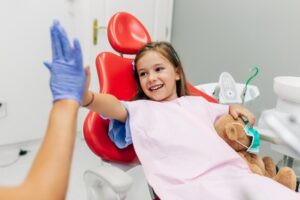 Young girl high-fiving her pediatric dentist 